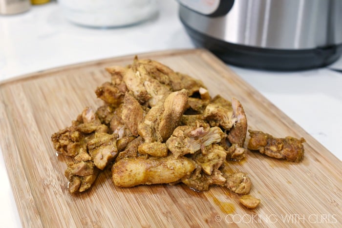 Cut cooked Chicken Shawarma into bite sized pieces on a bamboo cutting board.