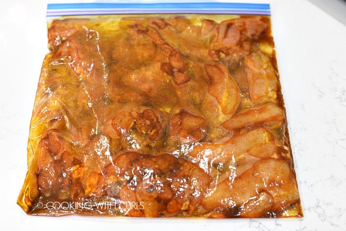 Marinated chicken in a large zipper topped plastic bag.