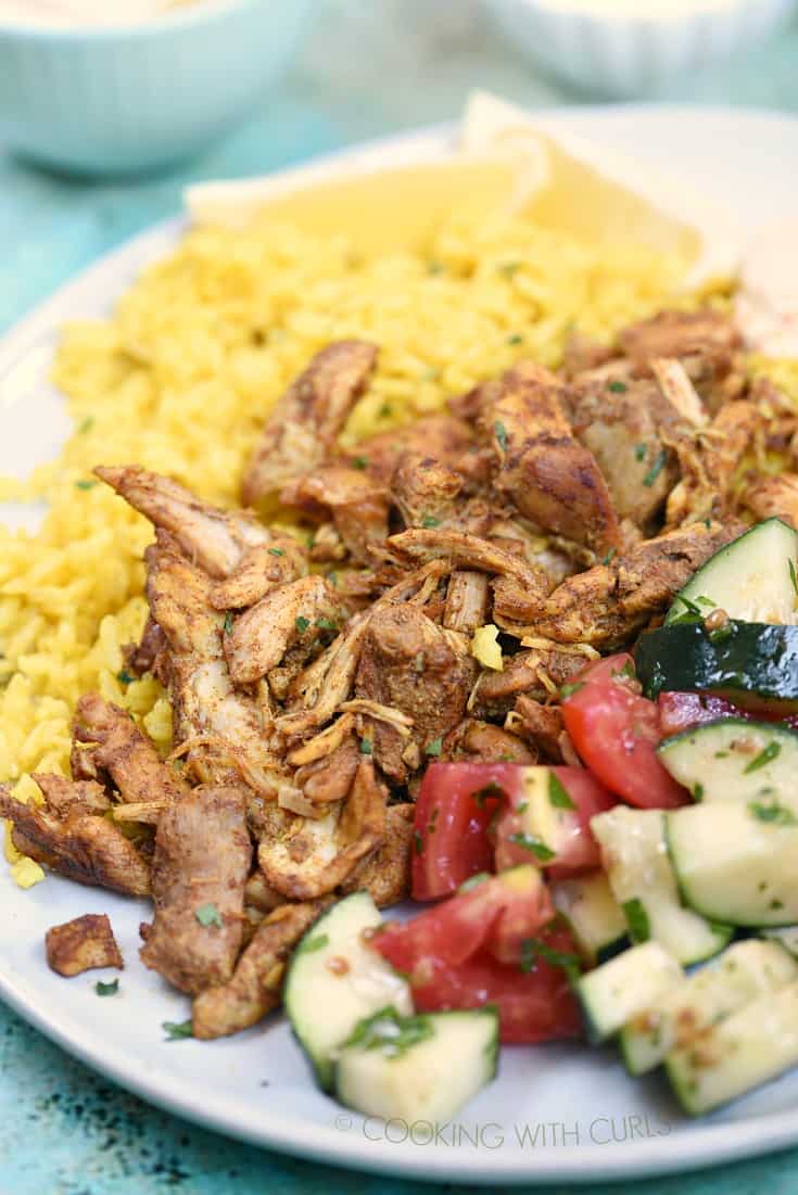 Instant Pot Chicken Shawarma on a white plate with yellow rice and cucumber and tomato wedges.
