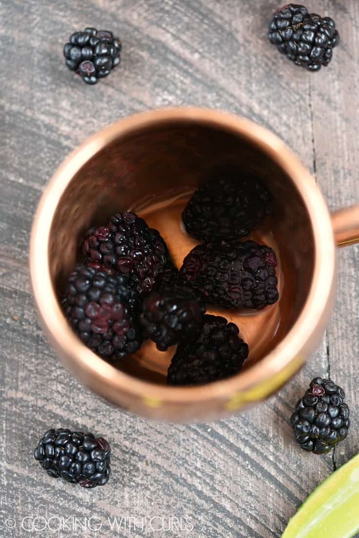 Add the blackberries and lime juice to a copper mug © COOKING WITH CURLS