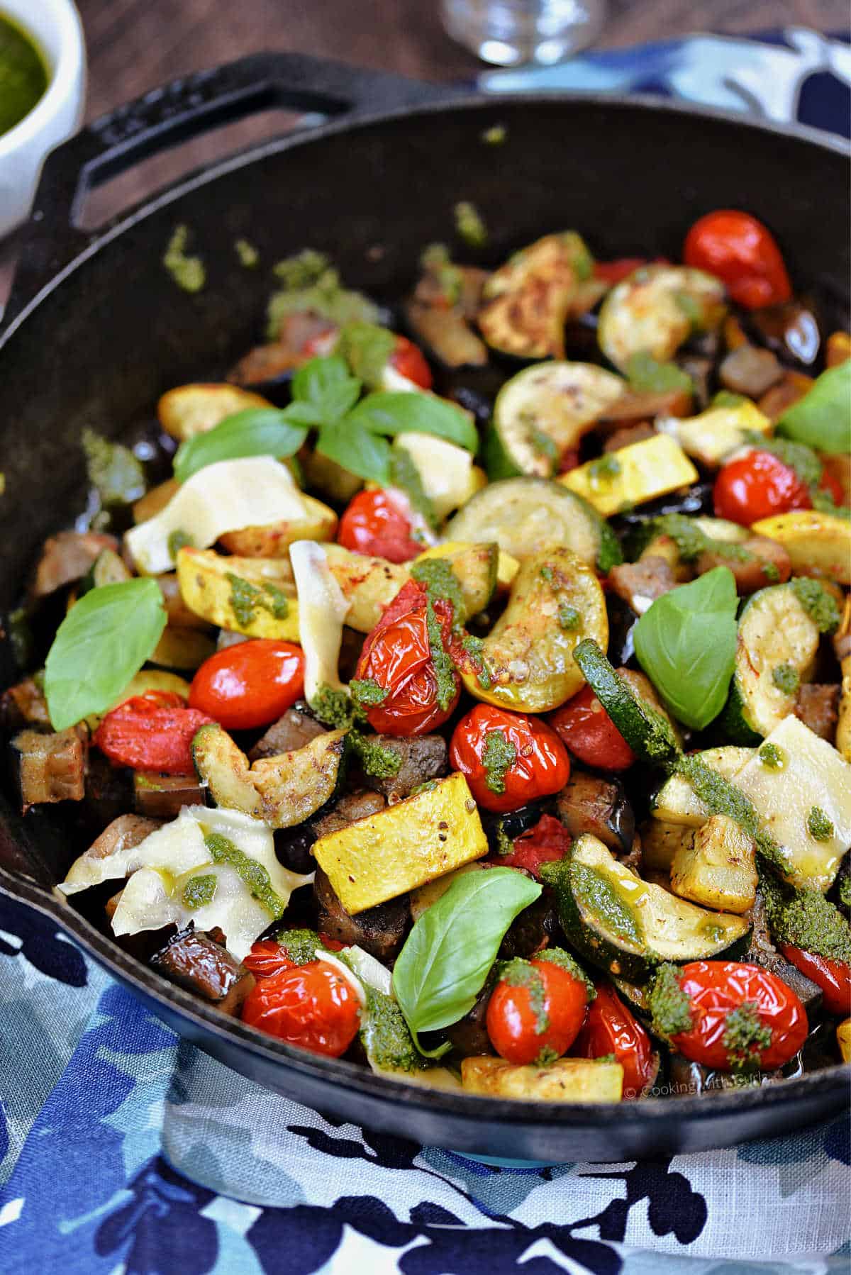 Charred zucchini, squash, eggplant, and cherry tomatoes in a cast iron skillet.
