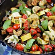 Charred zucchini, squash, eggplant, and cherry tomatoes in a cast iron skillet.