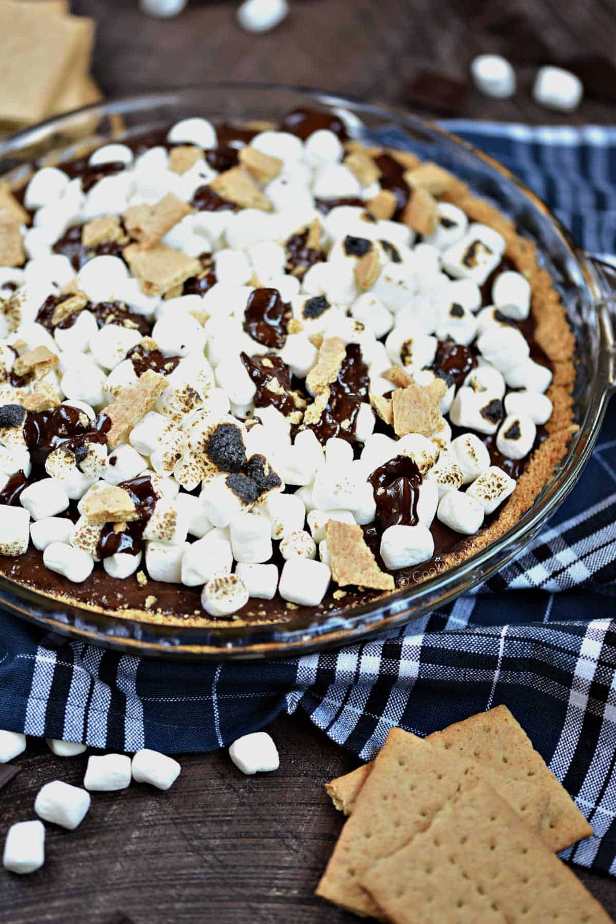 S'mores ice cream pie topped with mini marshmallows and graham cracker pieces in a pie dish.