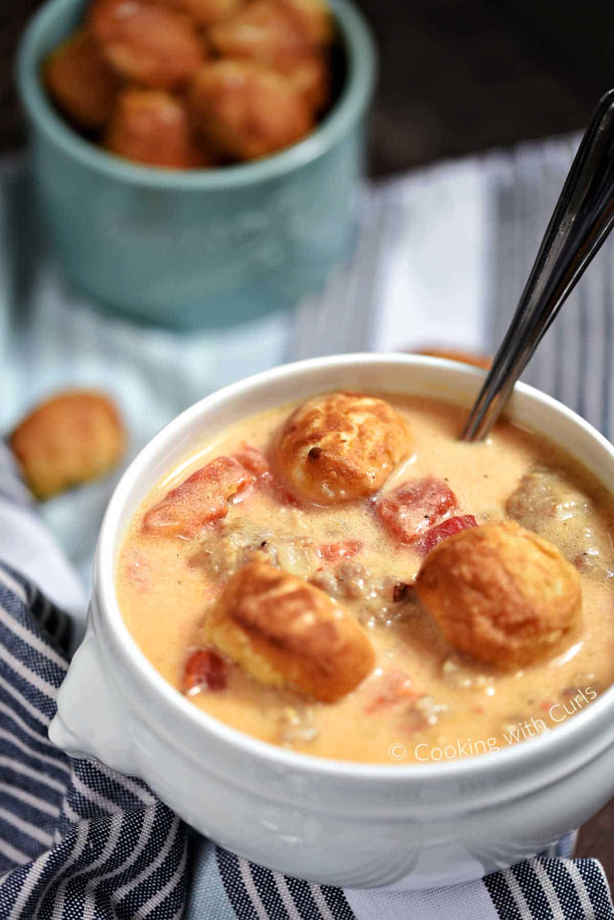 Brats and Beer Cheese Chowder topped with pretzel bites in a soup bowl.
