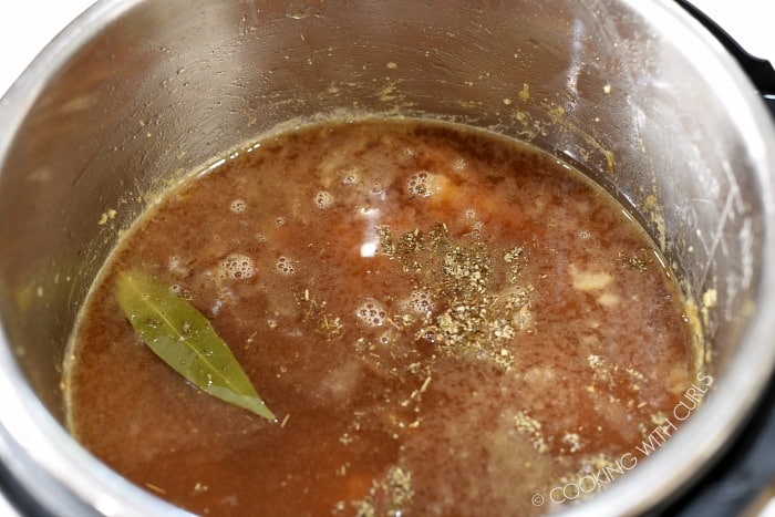 Beef broth and seasonings in a pressure cooker.