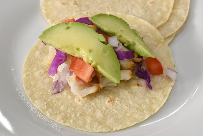 Top the Fish Tacos with cabbage, tomatoes, onions, and avocado cookingwithcurls.com