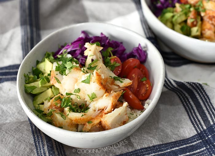 Top the cauliflower rice, tomatoes, avocado and cabbage with chunks of baked cod cooking withcurls.com