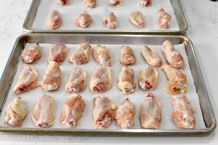 Chicken wings lined up on a parchment lined baking sheet cookingwithcurls.com