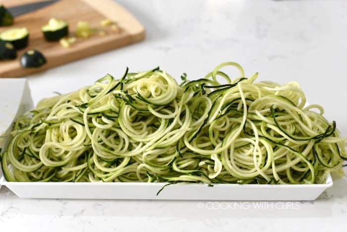 Fresh zucchini noodles spiralized into a tray.