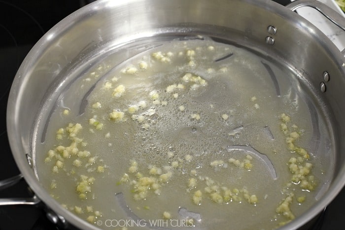 Melted butter and minced garlic sauteing in a large skillet cookingwithcurls.com