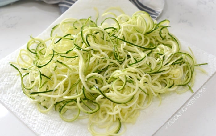 Spiral zucchini noodles laying on paper towels to drain 