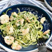 Zucchini noodle Shrimp Scampi with parmesan and parsley on a blue plate.