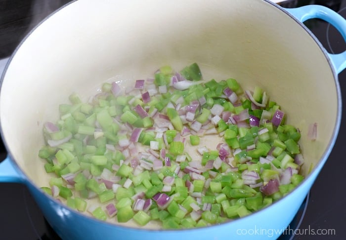 a large blue dutch oven with green pepper, celery and red onion sauteing