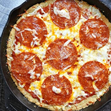 Keto Pizza Crust topped with sauce, melted cheese and pepperoni in a cast iron skillet recipe.