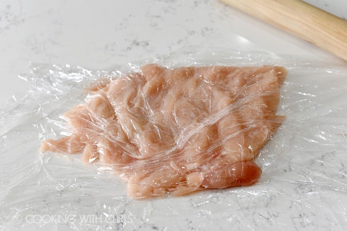 chicken breast sandwiched between two sheets of plastic wrap pounded until even with a rolling pin 