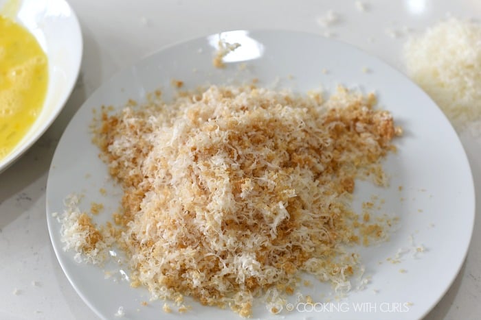 crushed pork rinds mixed with grated Parmesan cheese and seasonings on a white plate 