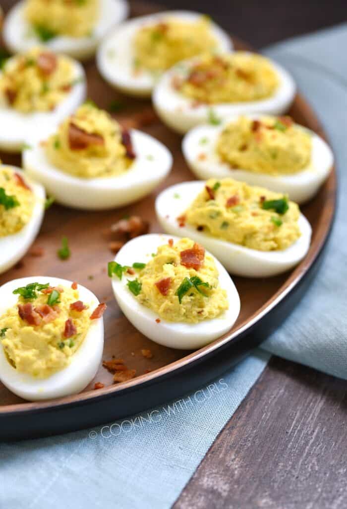 bacon ranch deviled eggs on a wooden plate sitting on a blue napkin