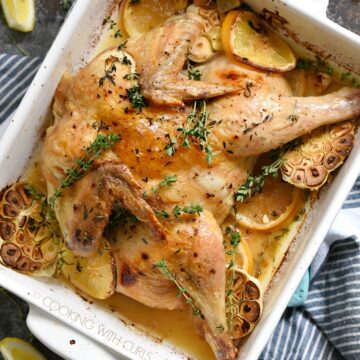 roasted spatchcock chicken in a white baking dish sitting on a blue and white striped napkin