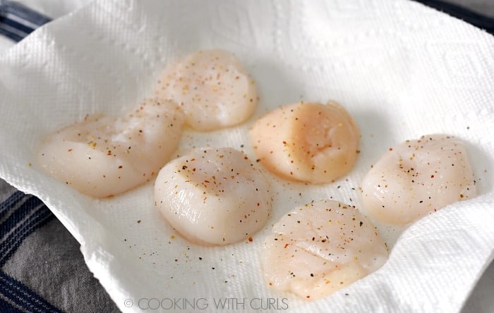 Scallops seasoned with garlic pepper on a paper towel lined plate 