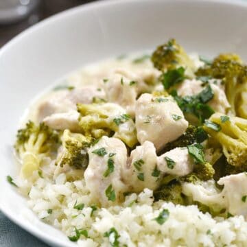 chopped chicken and broccoli in a cheese sauce served over cauliflower rice in a white bowl