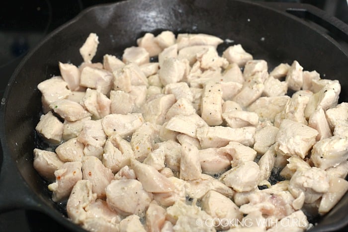 chicken pieces cooking in a cast iron skillet 
