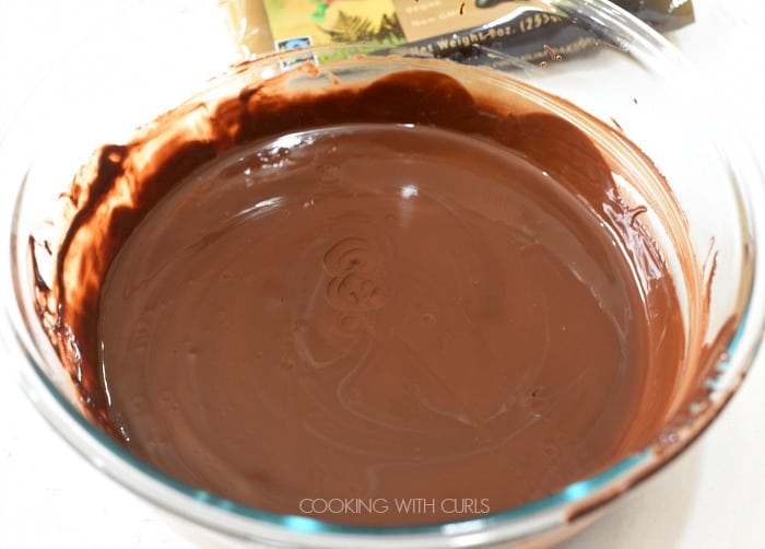 A bowl of melted chocolate in a clear glass bowl with mint oil added 