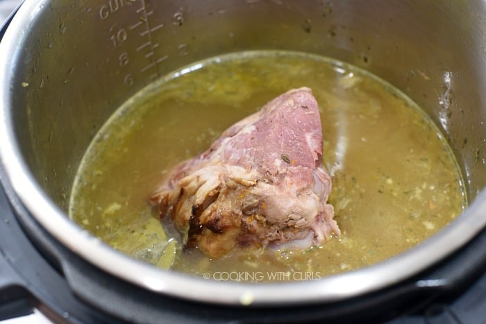 A ham bone added to the metal liner of the pressure cooker with the chicken stock and vegetables 