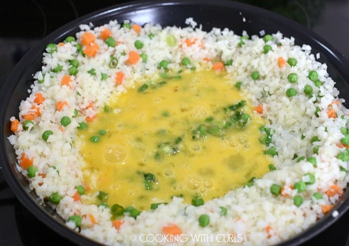 Beaten eggs added to the green onions in the center of the rice, peas and carrots