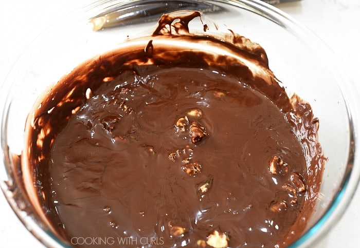 Melted chocolate and cocoa butter chunks mixed together in a clear glass bowl 