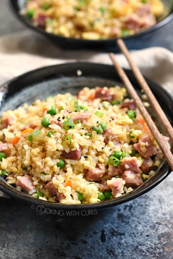 two bowls of ham fried rice with wood chop sticks on the edge of the bowl and a beige napkin between the bowls