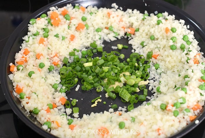 Rice, carrots and peas pushed to the sides of the pan to create a hole for the green onions 
