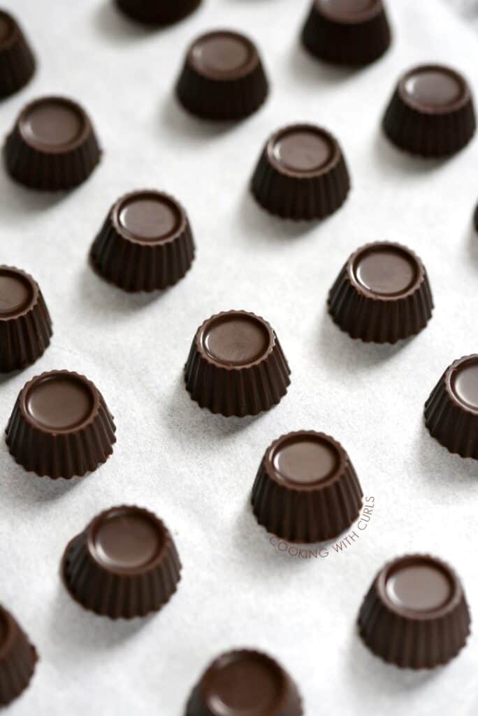 small dark mint chocolate fat bombs lined up on a piece of white parchment paper