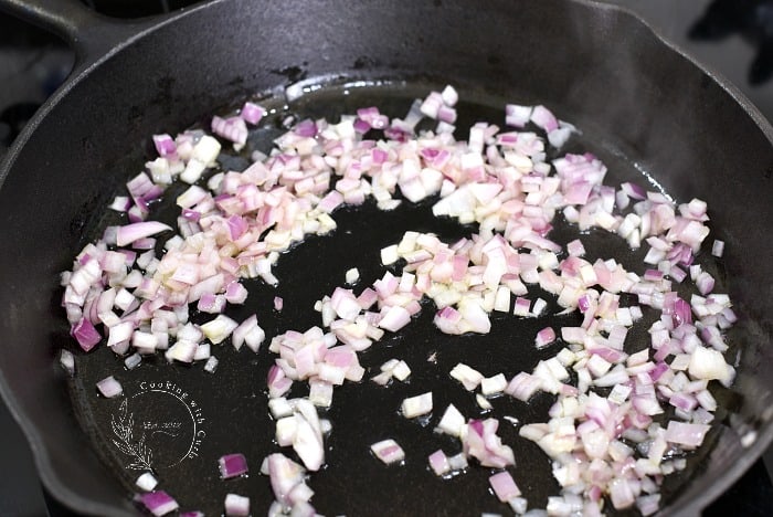 Diced red onion cooking in a cast iron skillet 