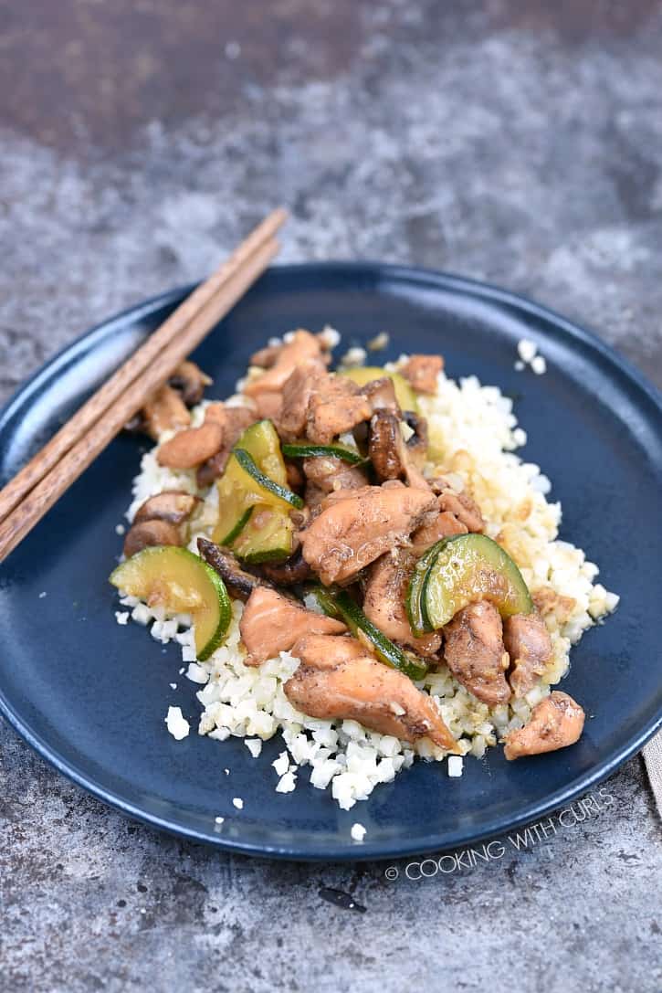 Instant Pot Chinese Garlic Chicken served over rice on a blue plate with wooden chopsticks in the upper right hand corner