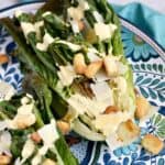 Grilled romaine lettuce topped with Caesar dressing, shaved Parmesan and croutons on a large platter
