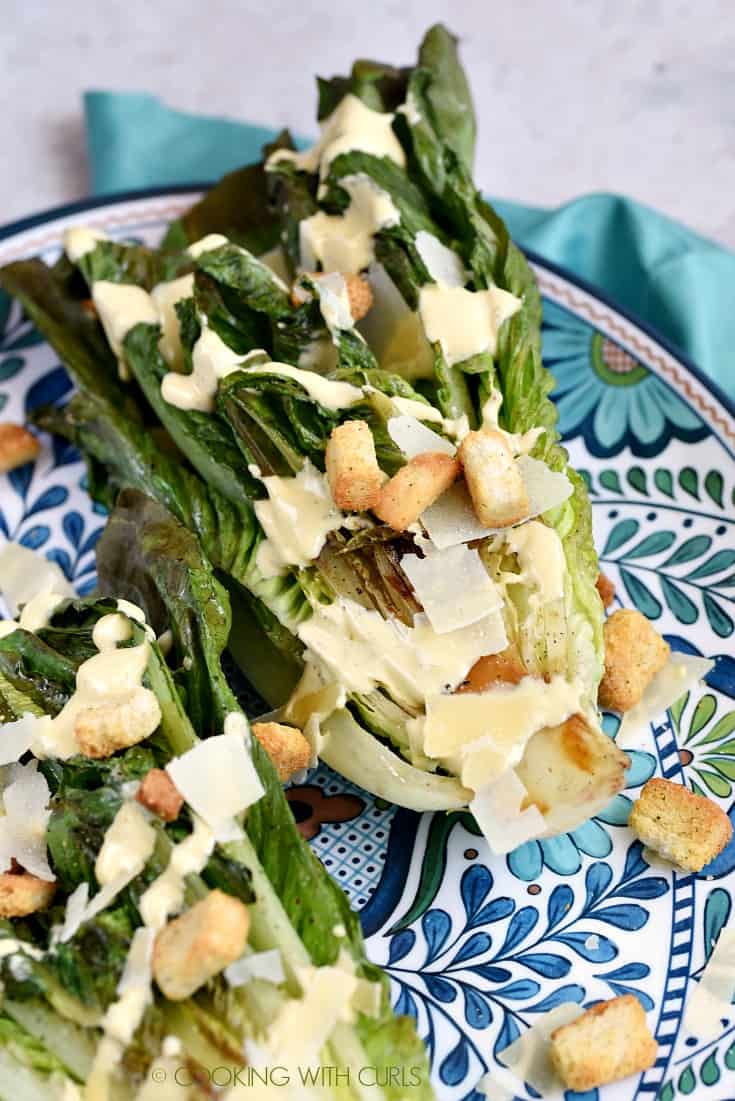 Grilled romaine lettuce topped with Caesar dressing, shaved Parmesan and croutons on a large platter