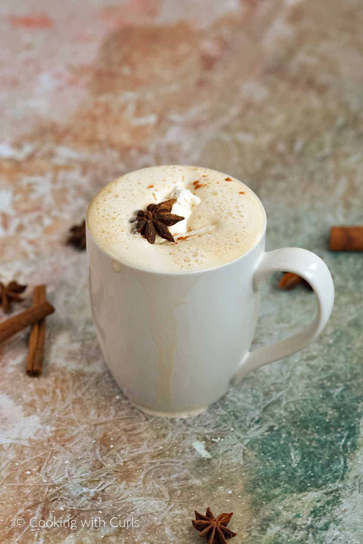 A Pumpkin Spice Latte in a white mug topped with whipped cream.