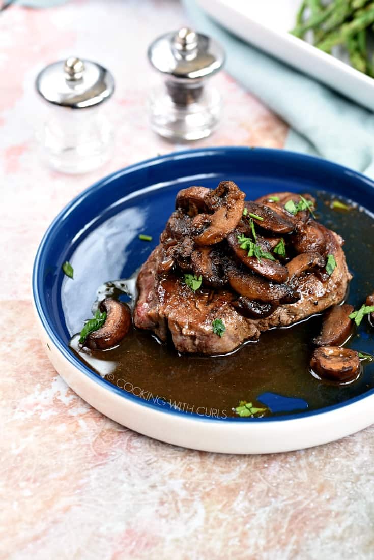 Steak Marsala topped with mushroom sauce on a blue plate