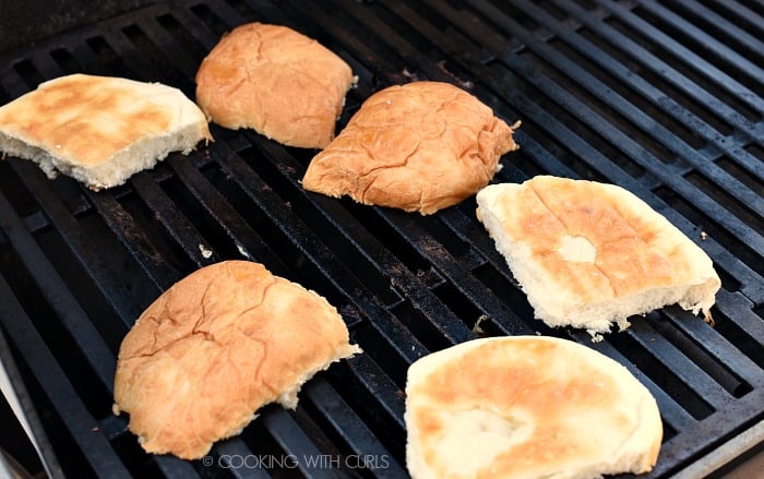 Three burger buns sliced in half and toasted on the grill. 