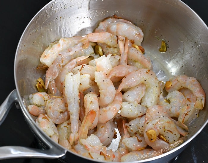 Raw shrimp tossed with the garlic-lemon infused oil in the saucepan 
