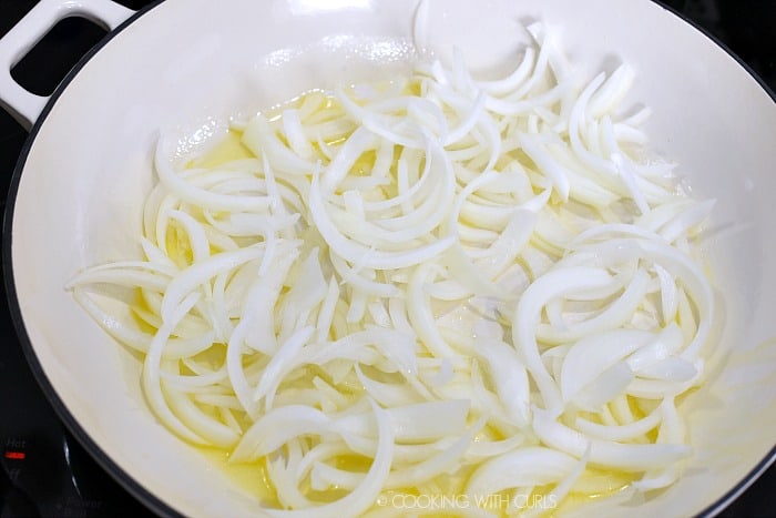 Thinly sliced onions slowly cooking in melted butter in a cast iron skillet 