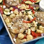Chicken and vegetables on a sheet pan, topped with feta cheese