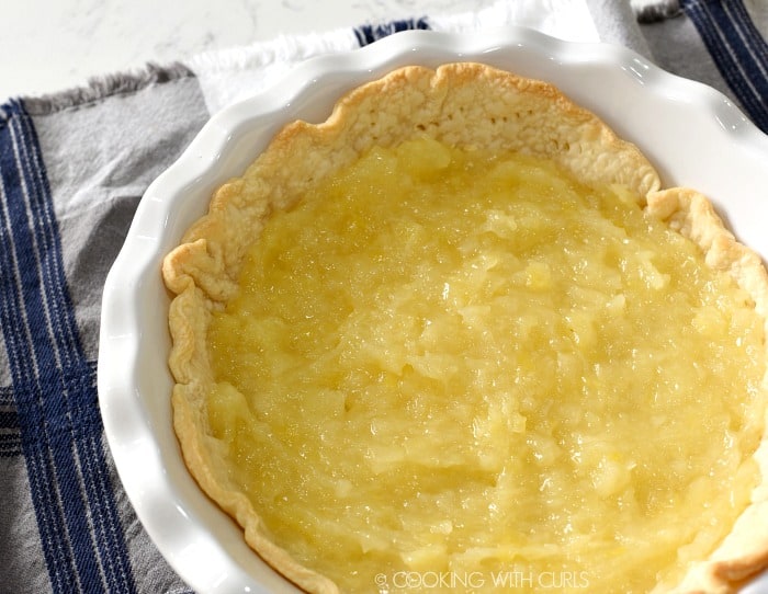 Pineapple filling spread over the baked pie crust in the pie dish