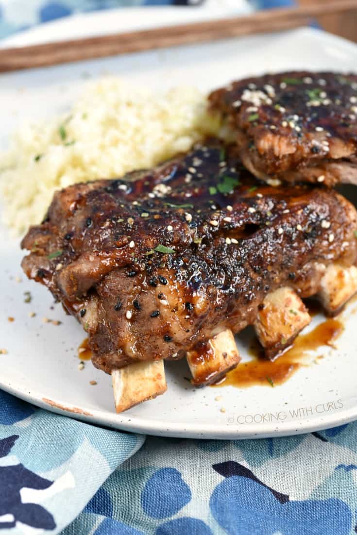 A close up of Instant Pot Teriyaki Ribs stacked on a plate with cauliflower rice