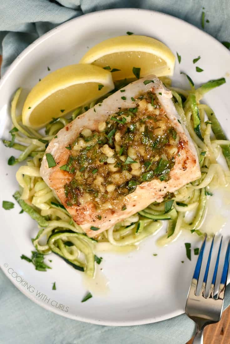 Looking down on a mahi mahi fillet on a bed of zucchini noodles topped with lemon garlic sauce