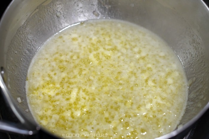 A saucepan with melted butter, minced garlic and shallots