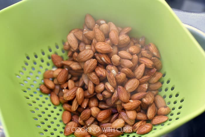 Boiled almonds drained in a green colander. 