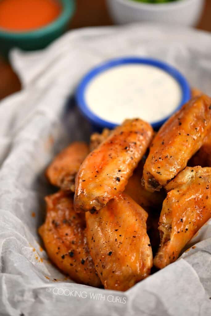 Baked Buffalo Chicken Wings with a side of Ranch dressing in a parchment paper lined basket