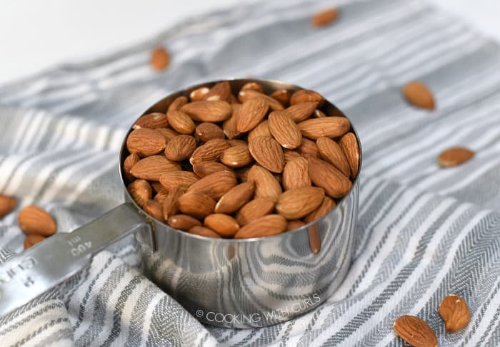 Raw almonds in a measuring cup.