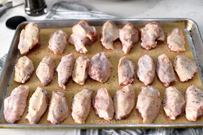 Raw chicken wings on a parchment lined baking sheet 